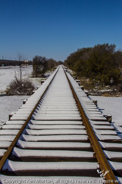 Snowy Railroad Headed Off Under Blue Sky